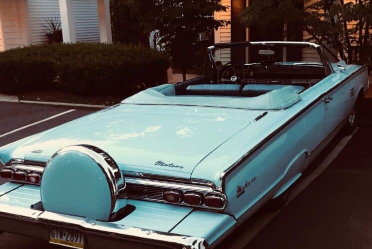 Antique turquoise convertible car from the fifties parked in a parking space