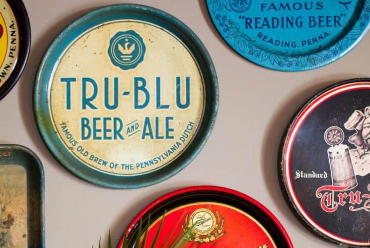 Antique serving trays decorated with different beer brands hanging on a wall