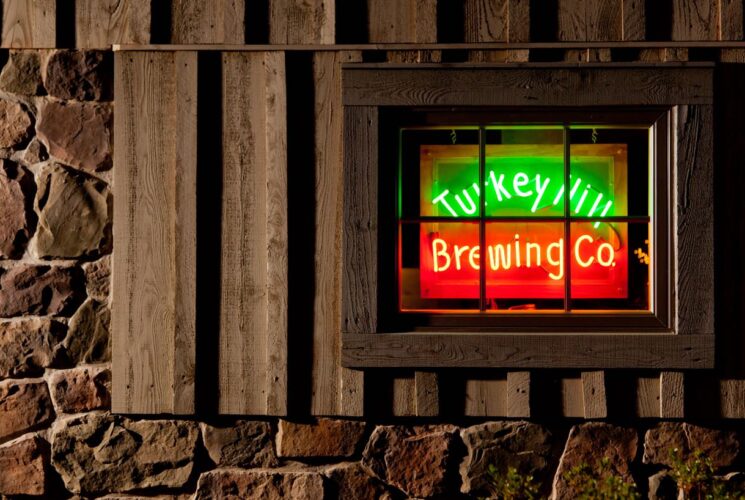 Close up view of window surrounded by stone brick with neon green and red Turkey Hill Brewing Co. sign