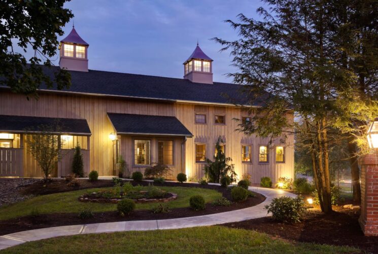 Exterior view of the Brewery at dusk surrounded by green shrubs, grass, and trees