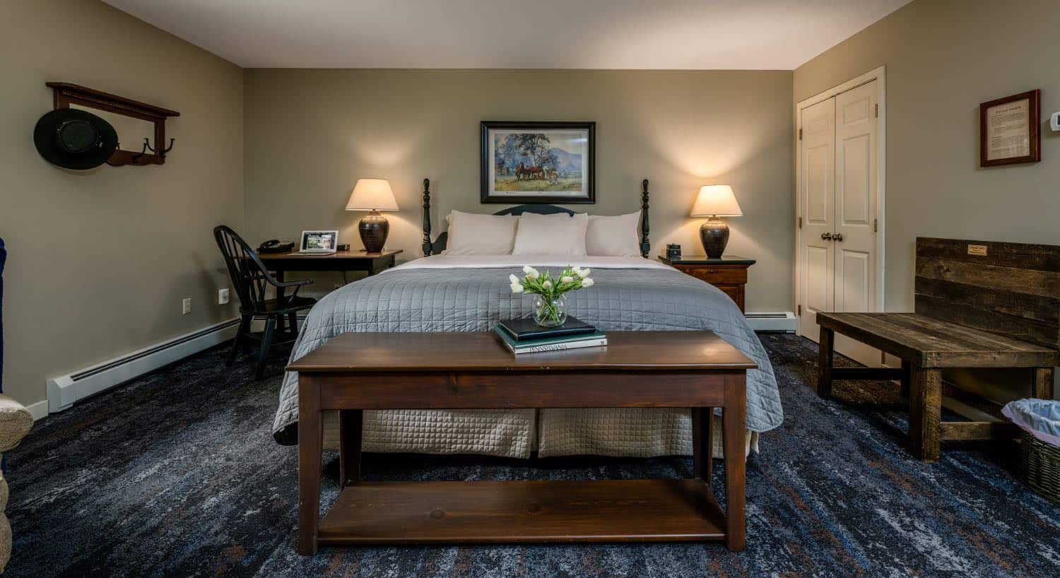 Bedroom with light gray walls, white trim, dark wooden headboard, white and blue bedding, and dark wooden desk and chair