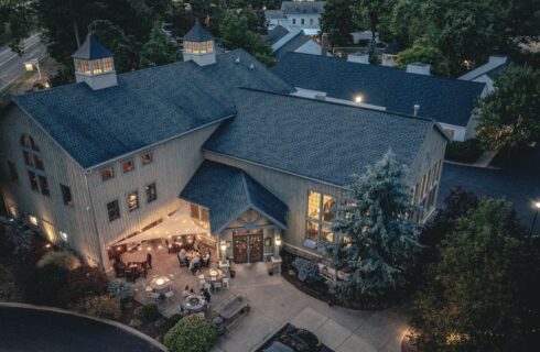 Exterior view of the Brewery at dusk surrounded by green shrubs, grass, and trees