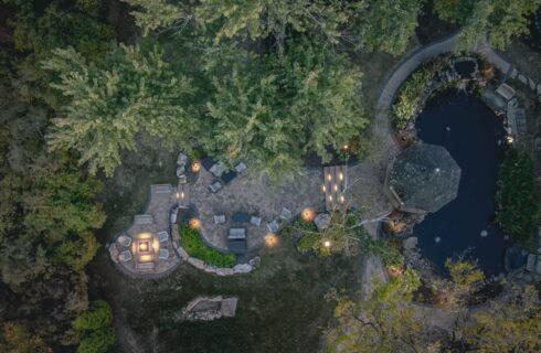 Aerial view of the property's pond, gazebo, and patio surrounded by green trees and vegetation