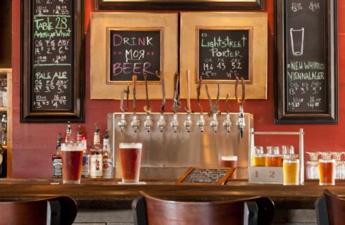 Wooden bar with beer taps and frames with beer prices on the wall