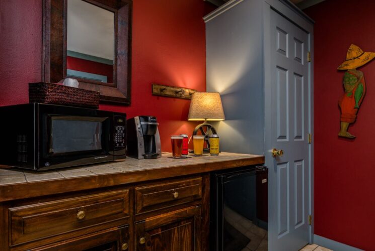 Bedroom nook with dark wooden cabinets, mini fridge, microwave, and coffee maker