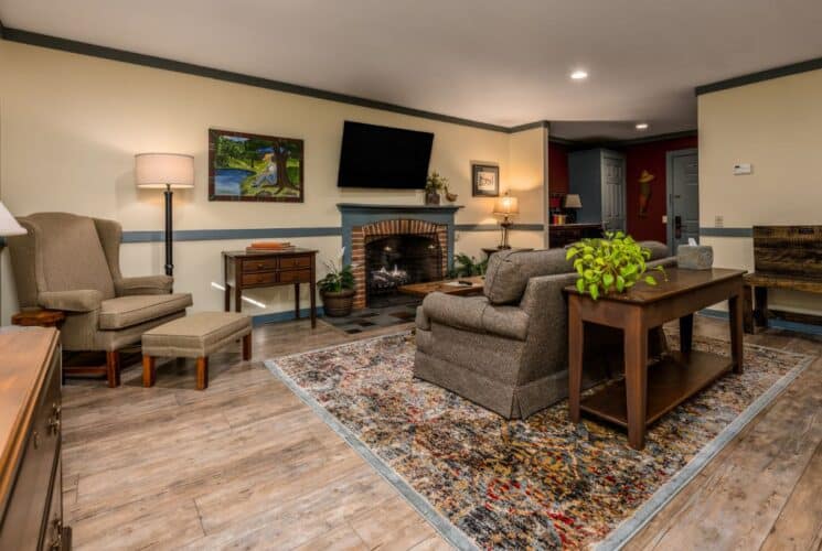 Bedroom with light yellow walls, blue gray trim, multicolored rugs, sitting area, and fireplace