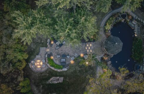 Aerial view of the property's pond, gazebo, and patio surrounded by green trees and vegetation