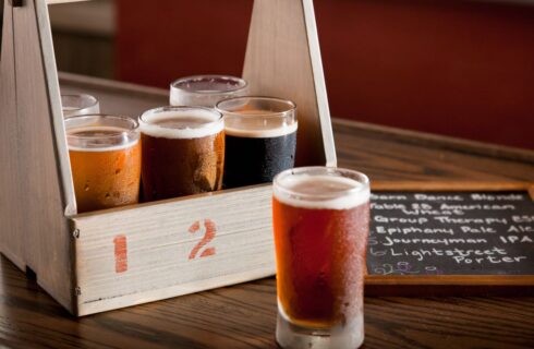 Close up view of wooden box with 6 different glasses filled with different types of beer