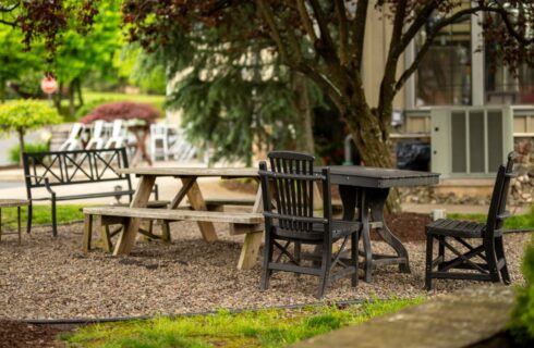 Picnic area near property nestled under trees with a wooden picnic table and dark wooden table and chairs