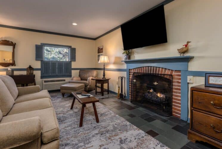 Bedroom with light yellow walls, blue gray trim, multicolored carpeting, sitting area, and fireplace