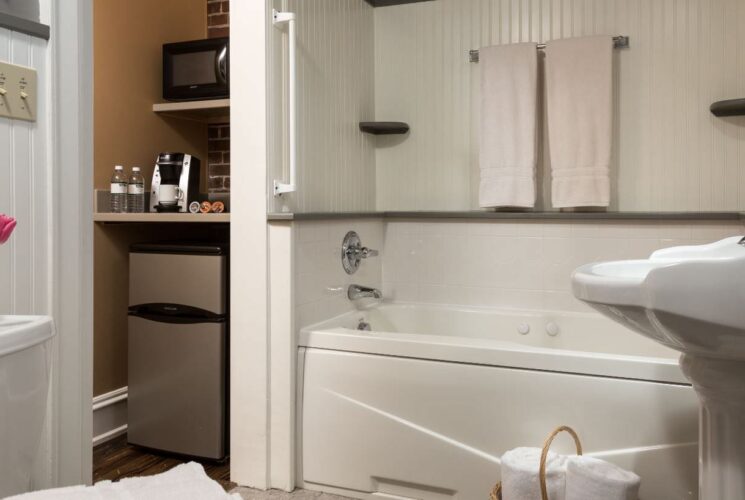 Bathroom with white-paneled walls, white pedestal sink, white toilet, and white bathtub