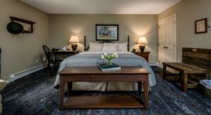 Bedroom with light gray walls, white trim, dark wooden headboard, white and blue bedding, and dark wooden desk and chair