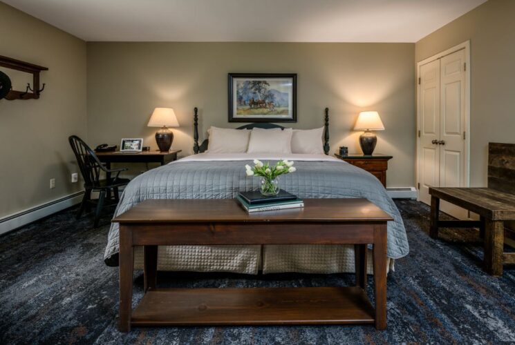 Bedroom with light gray walls, white trim, dark wooden headboard, white and blue bedding, and dark wooden desk and chair