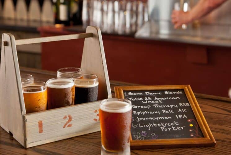 Close up view of wooden box with 6 different glasses filled with different types of beer