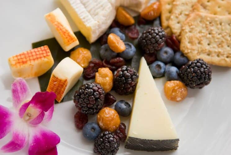 Close up view of cheese, crackers, berries, and raisins on a white plate