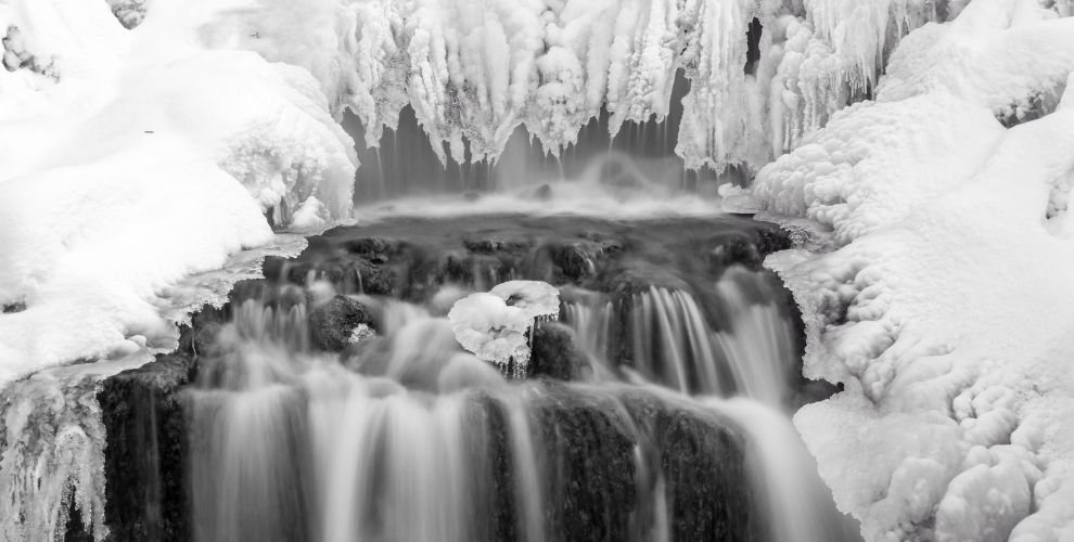 water flows under a frozen waterfall