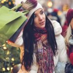 two ladies dressed warmly holding shopping bags and smiling looking at various shops